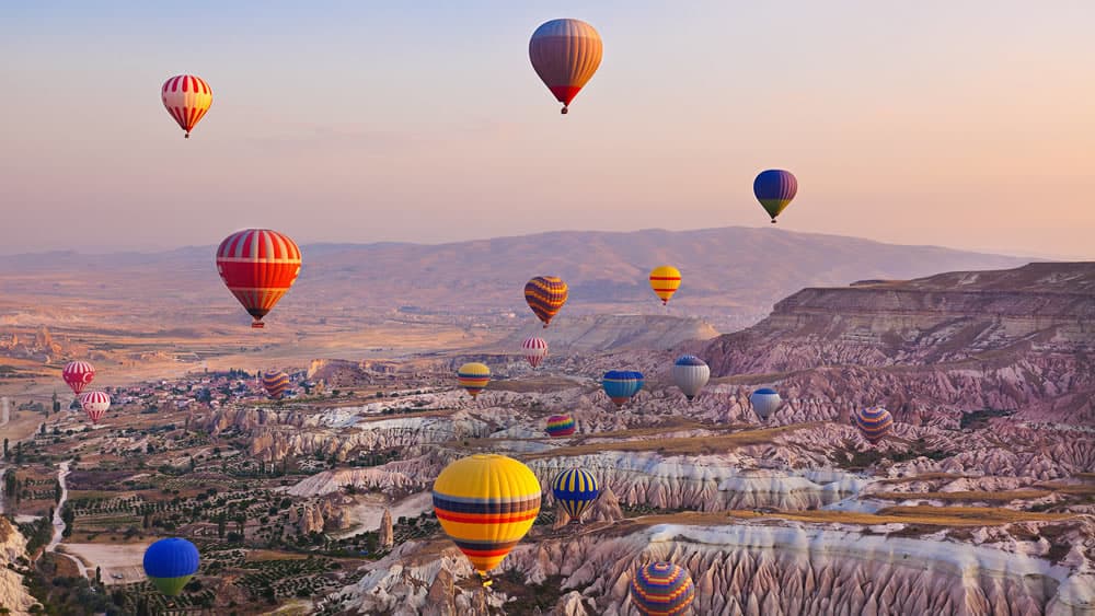 Hot air balloons soaring over the Cappadocia landscape at sunrise.