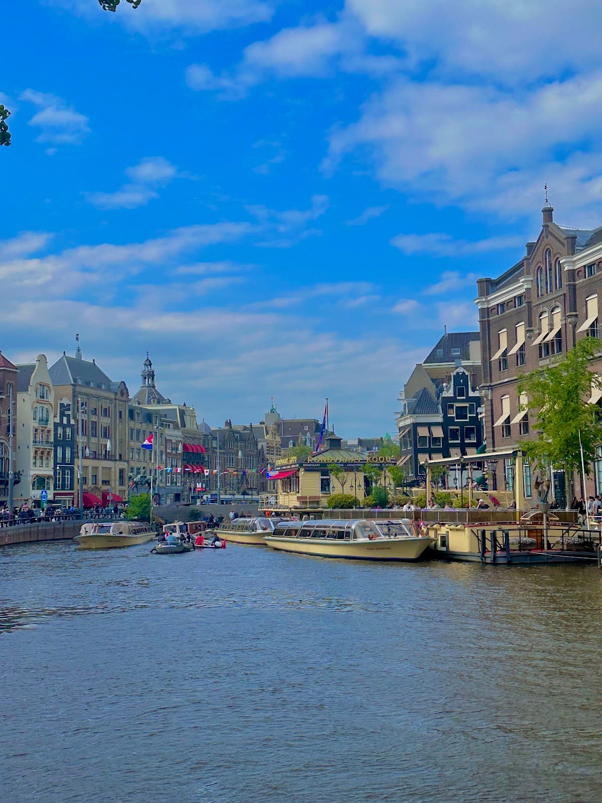 Iconic Amsterdam canal view with traditional architecture and tour boats.