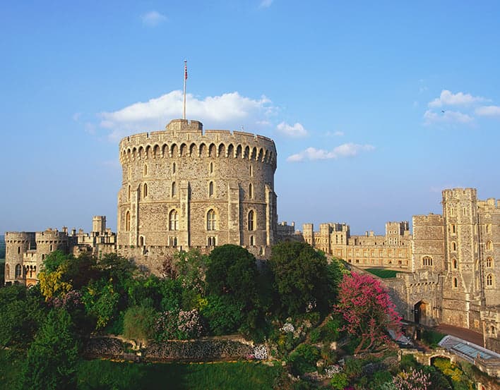 The iconic Round Tower of Windsor Castle surrounded by lush gardens.