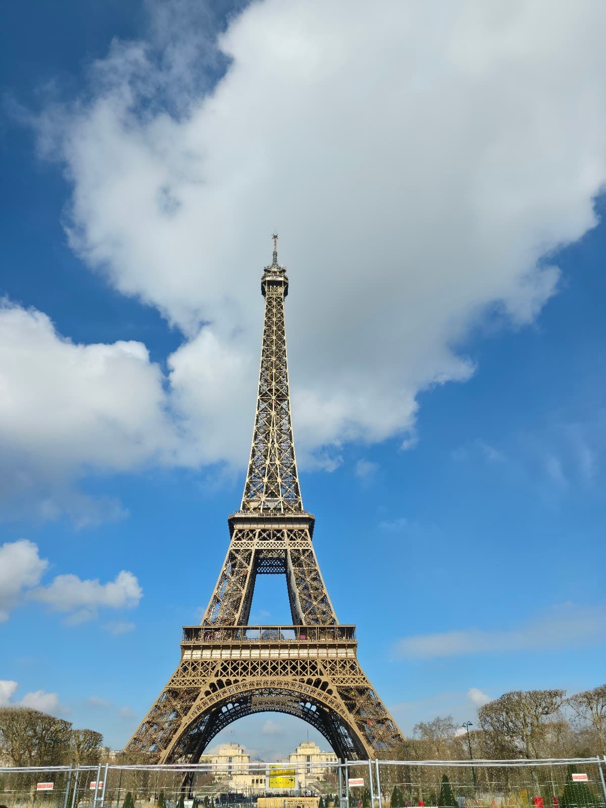 Iconic full view of the Eiffel Tower against a blue sky.