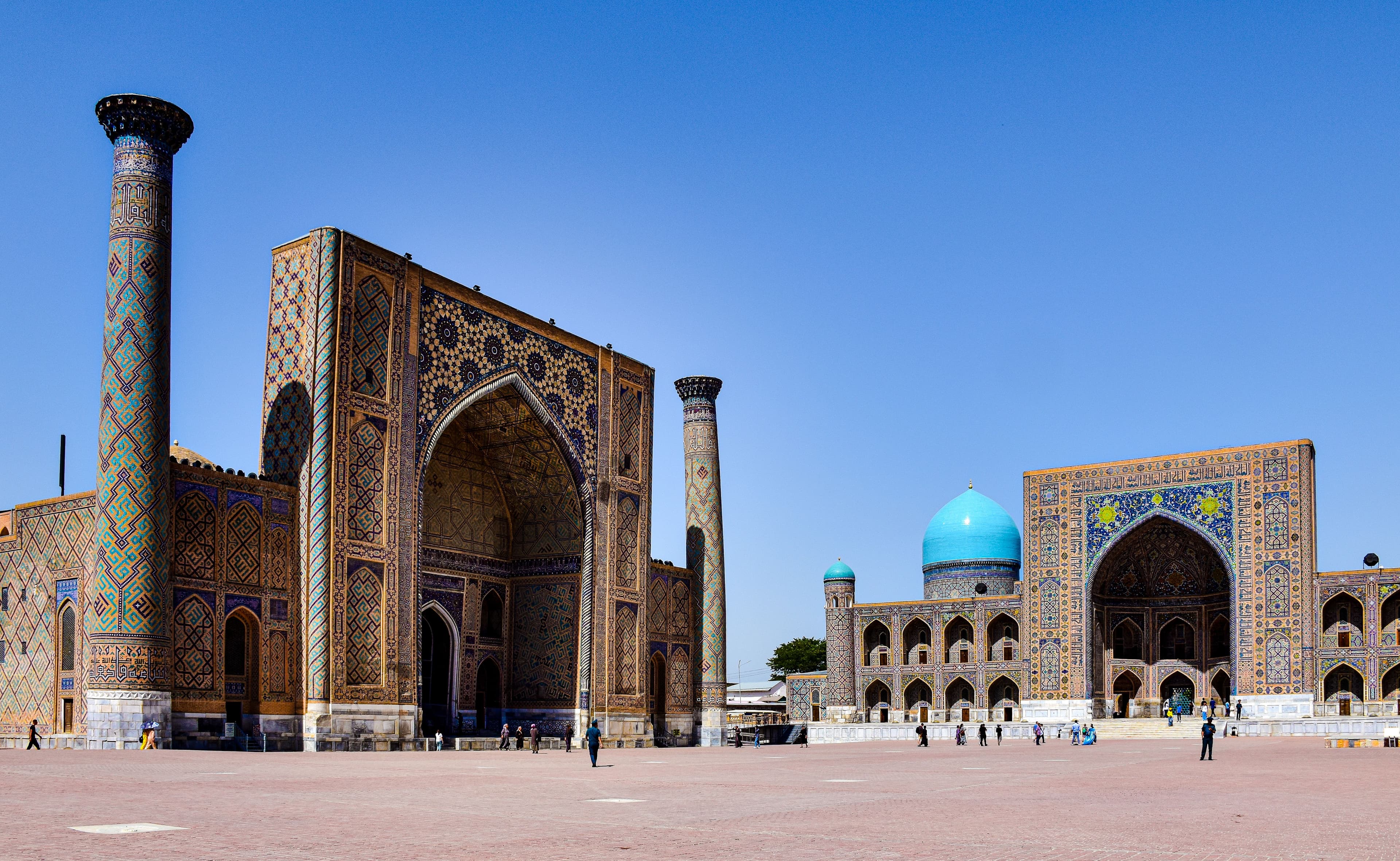 Wide view of the historic Registan Square madrasahs in Samarkand under a clear sky.