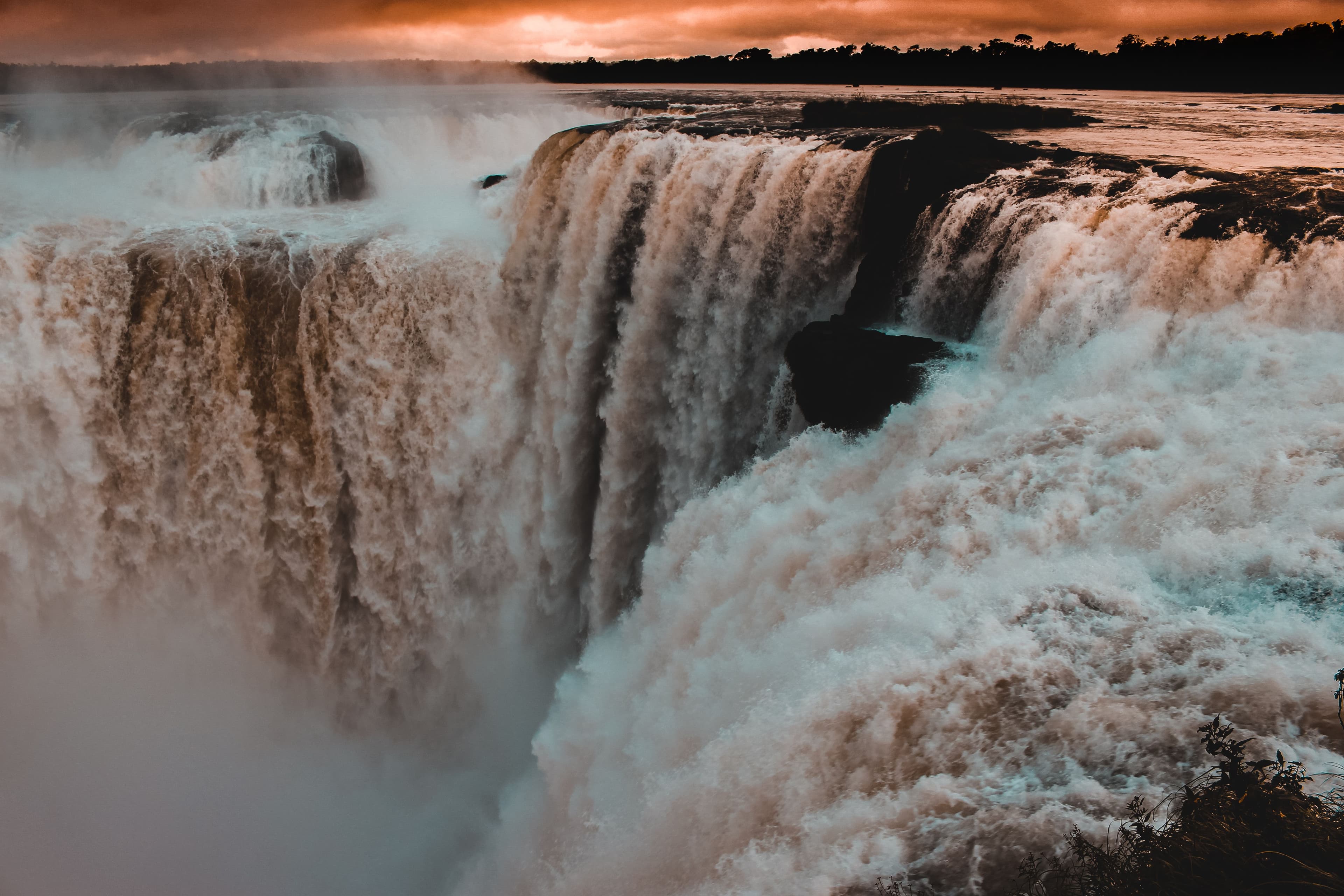 Dramatic sunset light illuminates the powerful cascading waters of the Devil's Throat at Iguazu Falls.