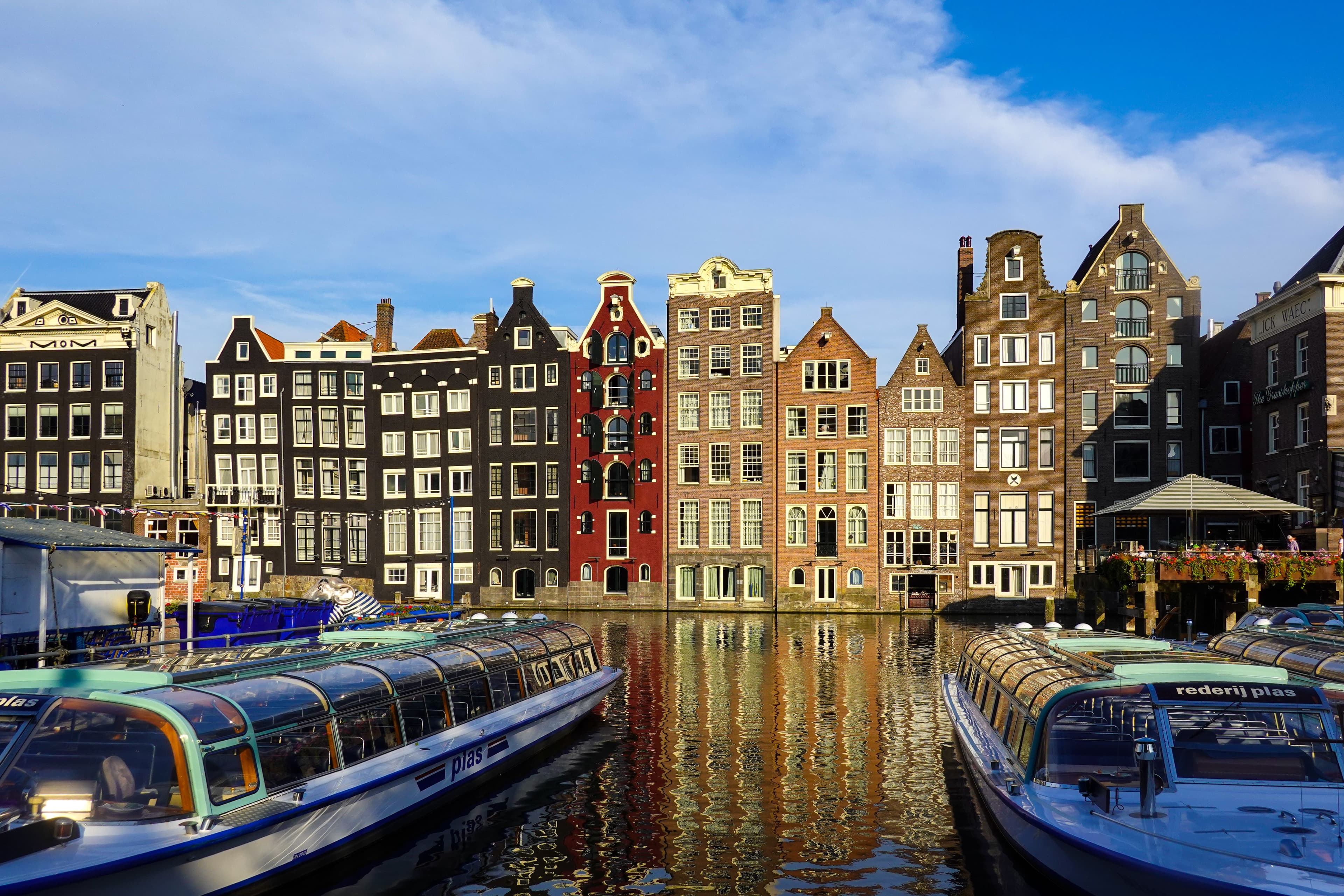 Stunning golden hour reflections of colorful Damrak canal houses.