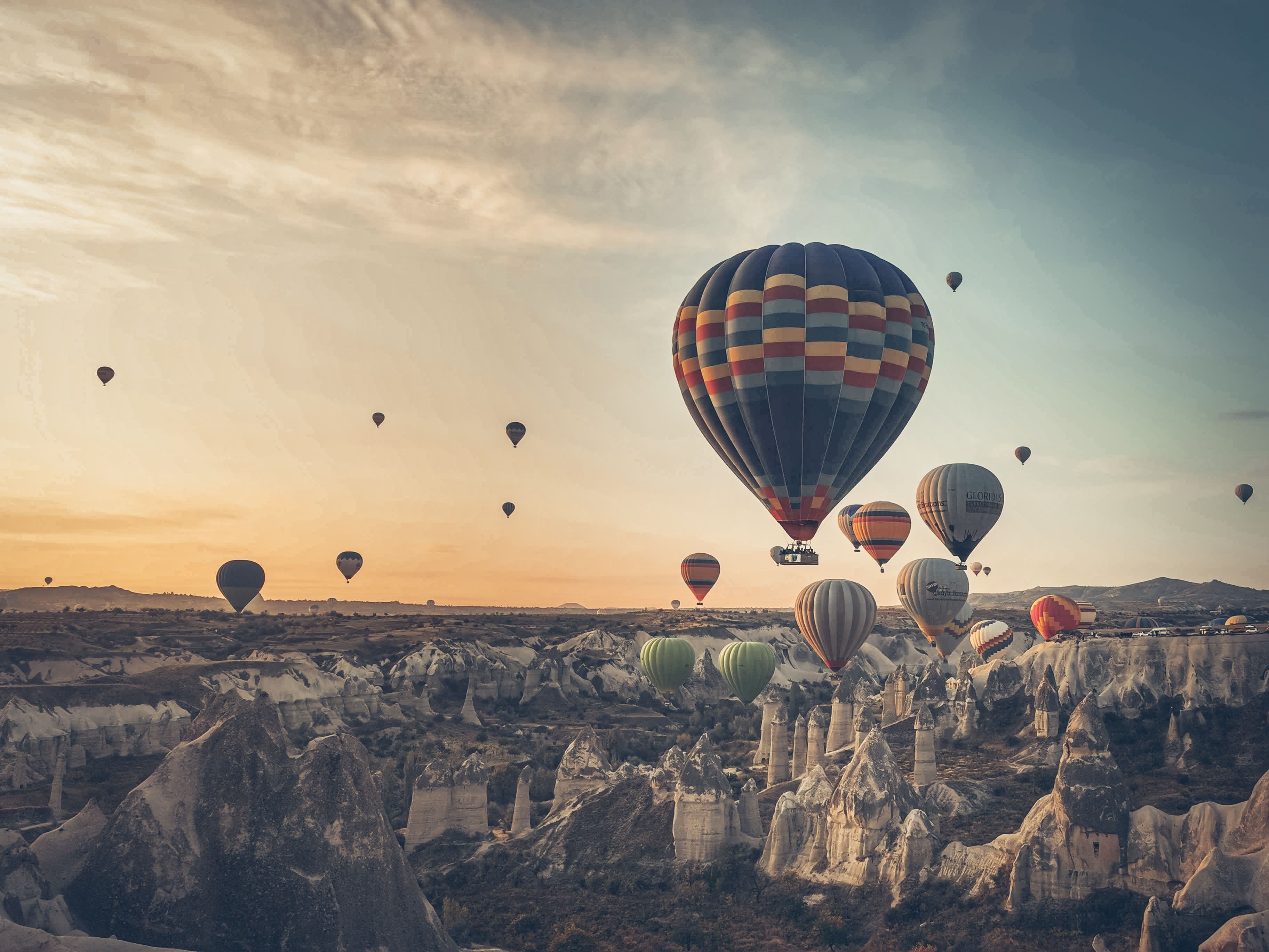 Hot air balloons floating over the unique rock formations of Cappadocia at sunrise.