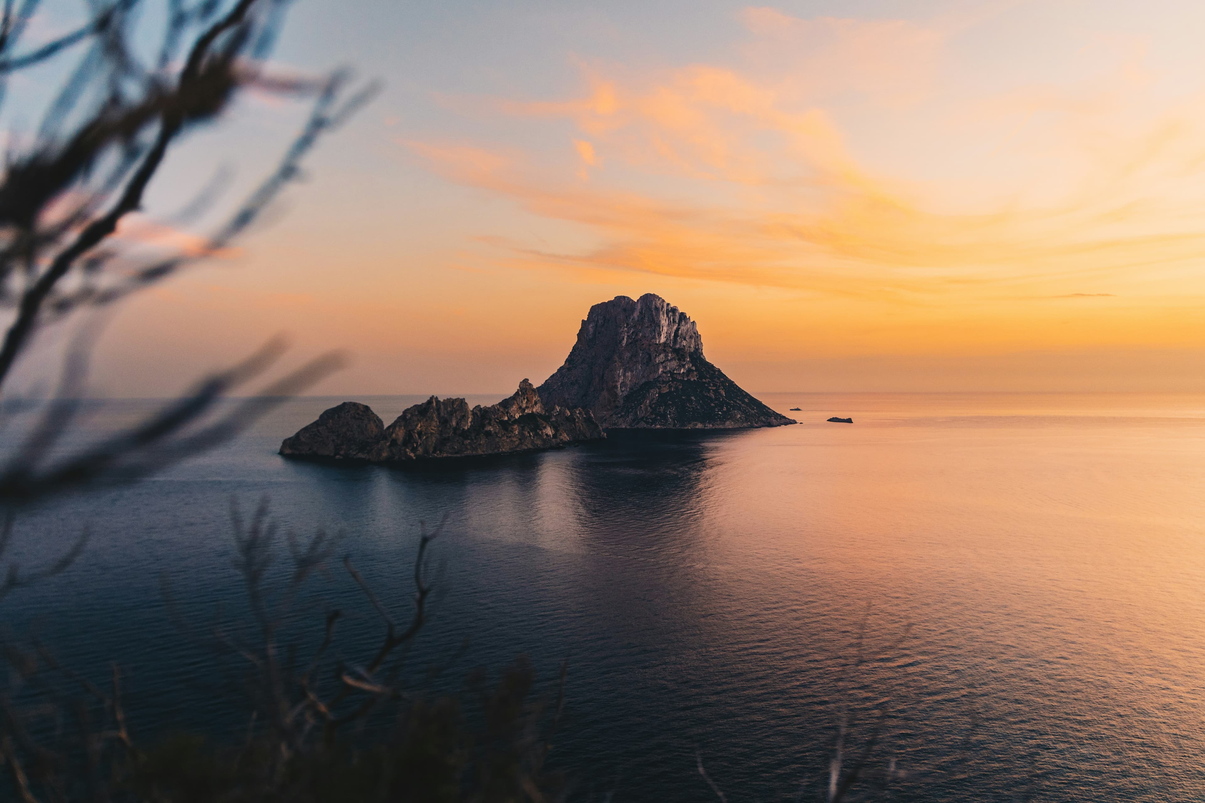 A breathtaking sunset glow over the mystical rocky island of Es Vedrà in Ibiza, Spain.
