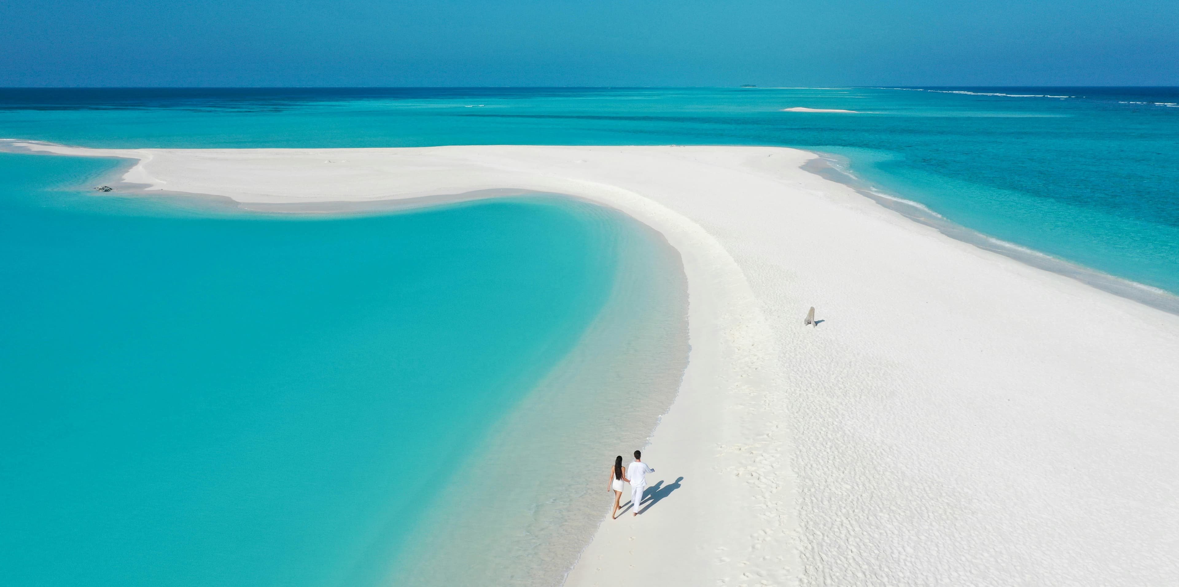 Breathtaking sandbank curve amidst vibrant turquoise lagoons.
