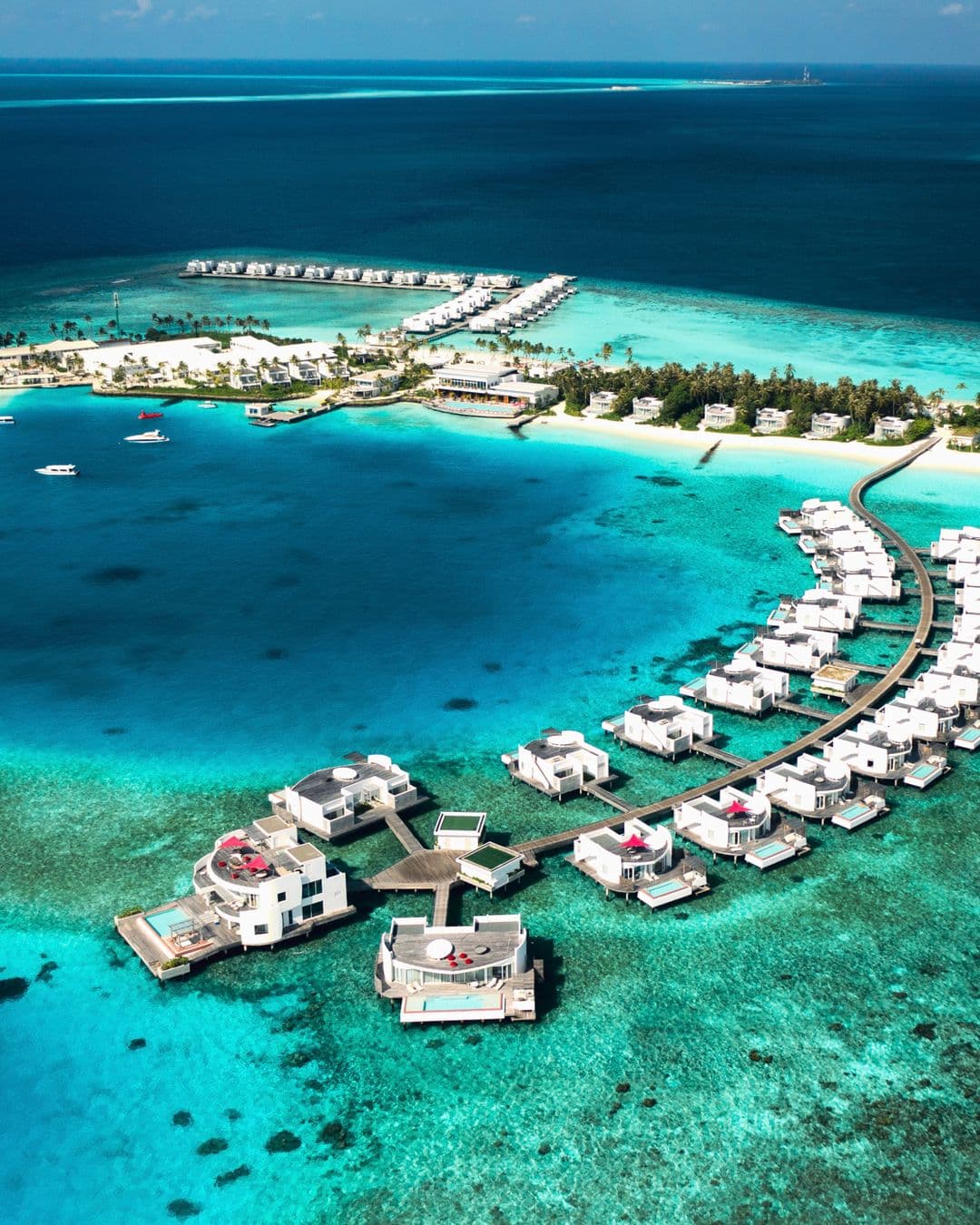Aerial perspective of modern circular overwater villas at Jumeirah Olhahali Island in the Maldives.